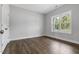 Bright bedroom featuring wood-look floors, white trim, large window, and neutral wall color at 3306 Leaflet Church Rd, Broadway, NC 27505