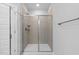 Modern shower with glass enclosure, beige tiled walls, a white base, and a convenient built-in shelf at 3306 Leaflet Church Rd, Broadway, NC 27505
