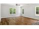 An open concept living room with three windows, hardwood floors, and a ceiling fan at 3328 Leaflet Church Rd, Broadway, NC 27505