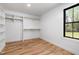 Walk-in closet featuring custom shelving, hardwood floors, and a window offering natural light and a backyard view at 3601 Bivins Rd, Hillsborough, NC 27278