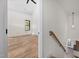 Bright hallway with wooden railing and flooring, leading to a spacious bedroom with large windows and hardwood floors at 3601 Bivins Rd, Hillsborough, NC 27278