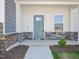 Inviting front porch featuring a blue door, stone accents, and manicured landscaping at 3717 Rosebush Dr, Zebulon, NC 27597