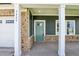Charming front porch with sturdy white pillars, a teal door, and brick accents for a welcoming entrance at 3829 Rosebush Dr, Zebulon, NC 27597