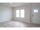 Bright living room with light wood-look flooring, two windows, and a white front door at 3829 Rosebush Dr, Zebulon, NC 27597