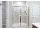Modern tiled shower with glass doors, chrome fixtures, and a built-in shelf at 3829 Rosebush Dr, Zebulon, NC 27597