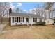 Charming single-story home with white siding, black shutters, and a cozy front porch seating area at 5144 Shield Cir, Raleigh, NC 27603