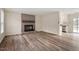Open-concept living space with wood floors, brick fireplace, and a glimpse into the kitchen at 5144 Shield Cir, Raleigh, NC 27603