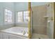 Bright bathroom featuring a bathtub under window and shower stall with glass door and tile surround at 5413 Leopards Bane Ct, Holly Springs, NC 27540