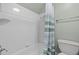 Bright, white tiled bath and shower combination featuring a striped shower curtain at 5413 Leopards Bane Ct, Holly Springs, NC 27540