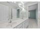 Bathroom with white cabinets, double vanity, large mirror, and doorway to adjoining room at 5413 Leopards Bane Ct, Holly Springs, NC 27540