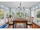 Bright dining room featuring large windows, plantation shutters, chandelier, and a table for six at 5413 Leopards Bane Ct, Holly Springs, NC 27540