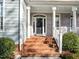 Inviting front entrance with brick steps, white pillars and a stylish front door at 5413 Leopards Bane Ct, Holly Springs, NC 27540