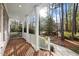 Inviting brick porch with white columns and railing, surrounded by a serene wooded view at 5413 Leopards Bane Ct, Holly Springs, NC 27540