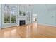 Open living room featuring tall windows, a fireplace, and hardwood floors at 5413 Leopards Bane Ct, Holly Springs, NC 27540