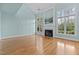 Empty living room featuring tall windows, a fireplace, and hardwood floors at 5413 Leopards Bane Ct, Holly Springs, NC 27540