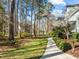 Well-maintained front yard with mature trees, lush green grass, and a walking path at 5413 Leopards Bane Ct, Holly Springs, NC 27540