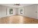 Bright bedroom with natural wood floors, two windows with white shutters, and a ceiling fan at 5815 Windham Dr, Raleigh, NC 27609