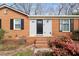 Charming brick home with a black front door and complementary landscaping and flower beds at 5815 Windham Dr, Raleigh, NC 27609
