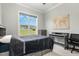 Well-lit bedroom boasts a ceiling fan, bright window, neutral walls, soft carpet, desk, and a comfortable queen bed at 5820 Brayton Park Pl, Holly Springs, NC 27540