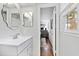 Bathroom vanity with modern mirror and white countertops with natural light from a window and doorway at 5920 North Hills Dr, Raleigh, NC 27609