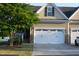 Inviting townhouse featuring a two-car garage, manicured lawn, and stone accents at 63 Radcliffe Ct, Clayton, NC 27527