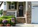 Charming home entrance with stone accents, a wreath, and potted plants for inviting curb appeal at 63 Radcliffe Ct, Clayton, NC 27527