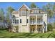 Rear view of home with multi-level deck, well-manicured lawn, and mature trees at 65 Gentle Winds Dr, Chapel Hill, NC 27517