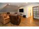 Living room with seating, TV and hardwood floors with an open doorway to the bath at 7004 Bartons Bend Way, Raleigh, NC 27614