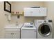 Laundry room with front-load washer and dryer, white cabinets, sink, countertop, and shelving at 80 Thornwhistle Pl, Garner, NC 27529