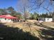 Expansive backyard featuring a storage building, a red-roofed house and mature trees at 9321 Stephenson Adams Ln, Willow Springs, NC 27592