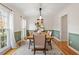 Dining room with half green walls, modern lighting, hardwood floors, and view of backyard at 112 Parkmeadow Dr, Cary, NC 27519