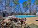 View of a community pool area surrounded by lush trees and a picnic table under the warm sun at 112 Parkmeadow Dr, Cary, NC 27519