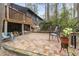 Backyard brick patio with seating near a home with a wooden deck and wooded surroundings at 118 Flora Mcdonald Ln, Cary, NC 27511