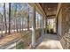 Covered front porch with stone columns and railings overlooks a lush, wooded front yard at 1196 Smith Creek Way, Wake Forest, NC 27587