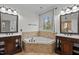 This primary bathroom boasts dual vanities, soaking tub, tile flooring, and bright window views at 1196 Smith Creek Way, Wake Forest, NC 27587