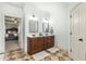 Bright bathroom boasts double vanity with dark wood cabinets, framed mirrors, and decorative tile flooring at 131 Tracker Ct, Garner, NC 27529