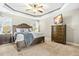Main bedroom with tray ceiling, ceiling fan, wood furniture, and a TV mounted on the wall at 131 Tracker Ct, Garner, NC 27529