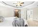 Bedroom featuring a trey ceiling, ceiling fan, plush carpet, a TV, and access to the main bathroom at 131 Tracker Ct, Garner, NC 27529