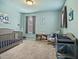 Bedroom featuring blue walls and carpeting with a crib and rocking chair at 1401 Wrenn Rd, Durham, NC 27703