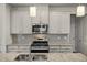 Modern kitchen with granite countertops, stainless steel appliances, and a stylish tile backsplash at 1401 Wrenn Rd, Durham, NC 27703