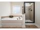 Bright bathroom featuring a garden tub with tile surround and a tiled shower with glass doors at 174 Coalyard Dr, Garner, NC 27529