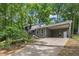 Traditional home exterior with a large driveway and a carport nestled within lush green trees at 202 Brook Ln, Durham, NC 27712