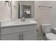 White bathroom features a vanity with under cabinet storage, a mirror, and a view into the kitchen at 261 Umstead St, Sanford, NC 27330