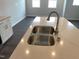 Close up of a kitchen island with a stainless steel sink, faucet, and quartz countertop with white cabinets at 3011 Honeymyrtle Ln, Durham, NC 27703