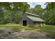 Barn with a green roof on a property featuring a fenced area and surrounded by trees at 3560 Nc 98, Youngsville, NC 27596