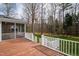 A view of the back porch with white railings and wood floor, a screened-in part, and trees in the background at 400 Tharps Ln, Raleigh, NC 27614