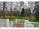 The backyard with a wooden deck and white railings, a grassy lawn, and trees in the background at 400 Tharps Ln, Raleigh, NC 27614