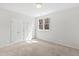 Sunlit bedroom with neutral carpet, double closets, and a large window at 400 Tharps Ln, Raleigh, NC 27614