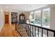 Hallway with a dark wood railing, wood floors, built-in bookcase and decorative lighting at 402 Westwood Dr, Chapel Hill, NC 27516