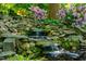 Backyard waterfall featuring rocks, moss, flowers and greenery at 402 Westwood Dr, Chapel Hill, NC 27516
